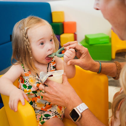 An adult helping a child self-feed with a TalkTools Itsy Rings spoon