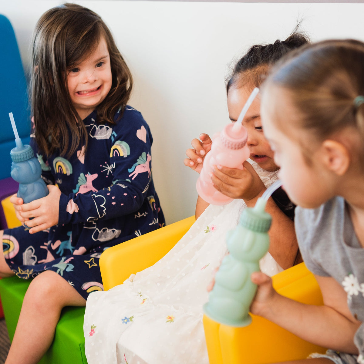 Three children each drinking from a TalkTools Honey Bear Silicone cup